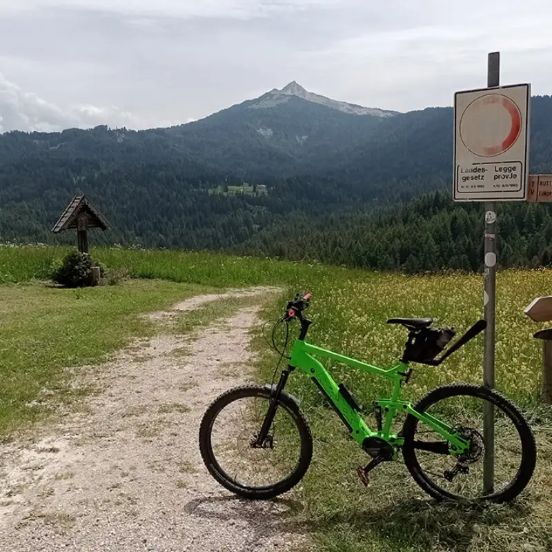 Das grüne Fahhrad von Christian Waniaus steht an einer Wegkreuzung inmitten grüner Wiesen in Südtirol